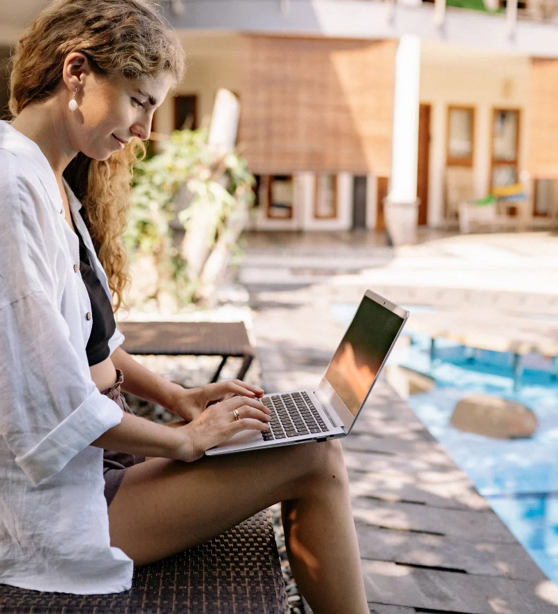 Prozesse automatisieren wie ein Profi - Frau sitzt mit Laptop auf den Beinen an einem Pool.